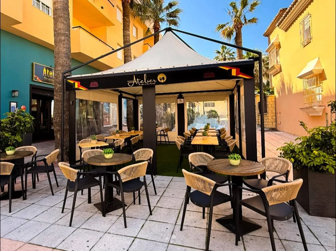 The Brasserie Atelier terrace set for service, with timber tables under a shaded awning