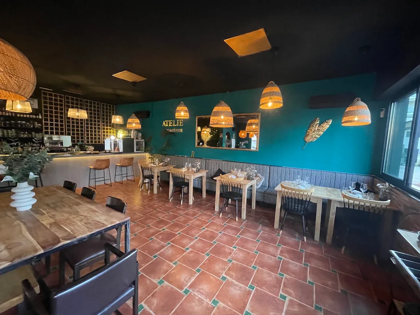 Inside Brasserie Atelier, with the bar, turquoise walls and warm lighting